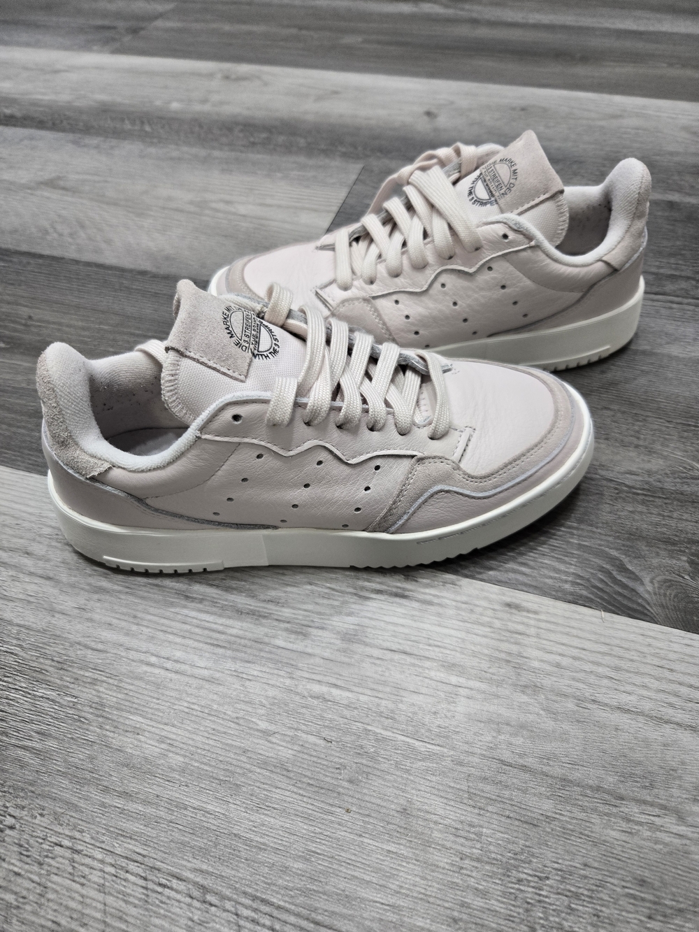 Adidas Originals Supercourt trainers in a pink orchid tint or raw white colorway
